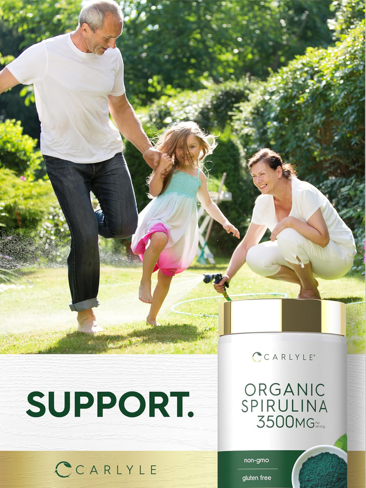 Family enjoying a sunny backyard with a sprinkler next to a Carlyle Organic Spirulina bottle.