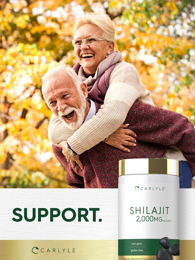 Laughing elderly woman rides piggyback on elderly man outdoors, holding Shilajit bottle.