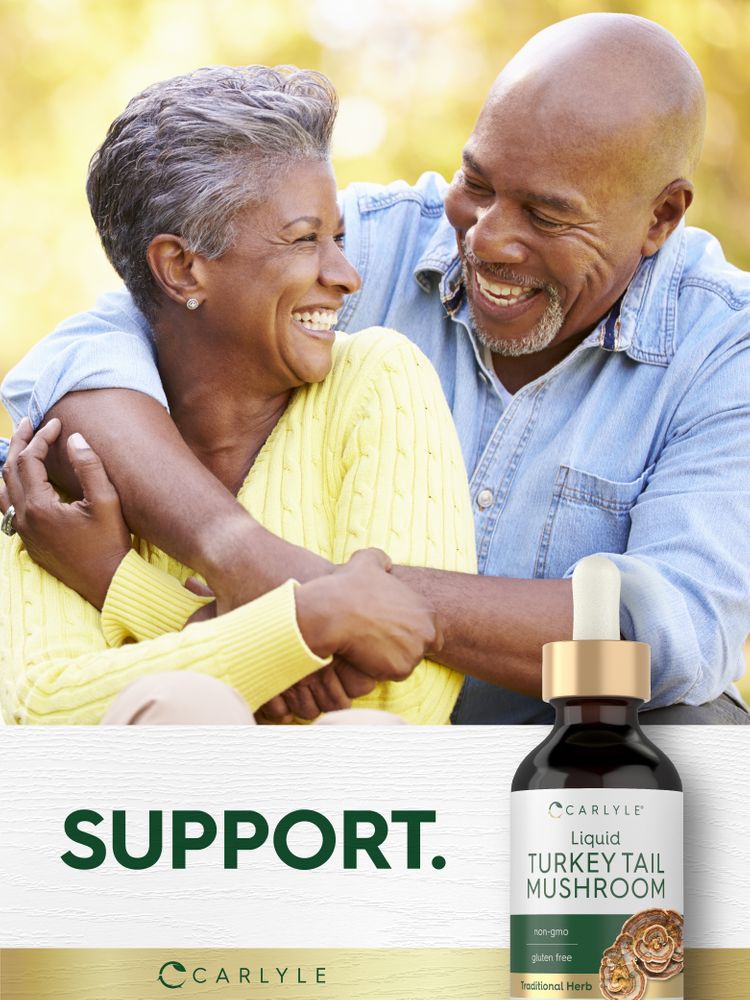 An elderly African American couple hugs and laughs while holding a bottle of Carlyle Liquid Turkey Tail Mushroom.