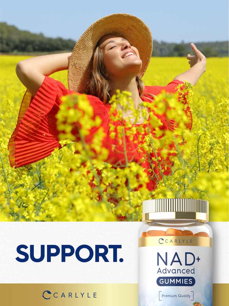 Young adult woman smiling in a field of yellow flowers with a Carlyle NAD+ Advanced Gummies bottle beside her enjoying the sun.