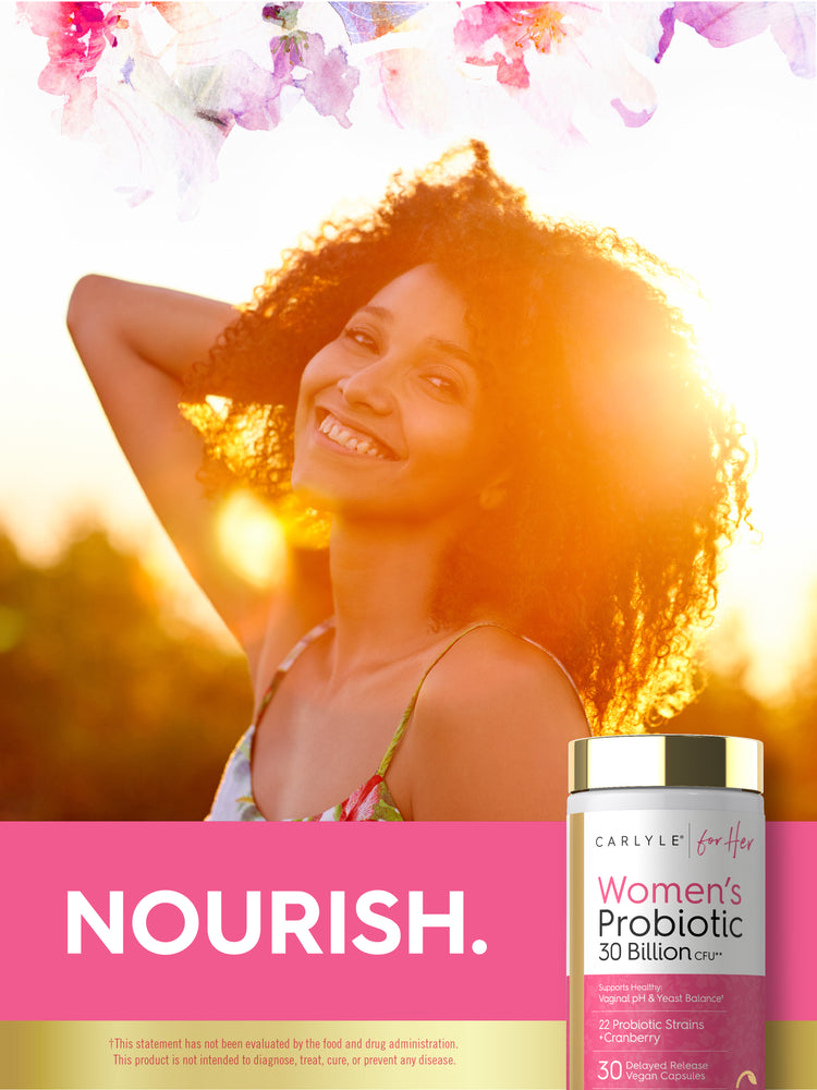Young woman smiling, back-lit by the sun, holding a Carlyle for Her Women's Probiotic 30 Billion CFU bottle.