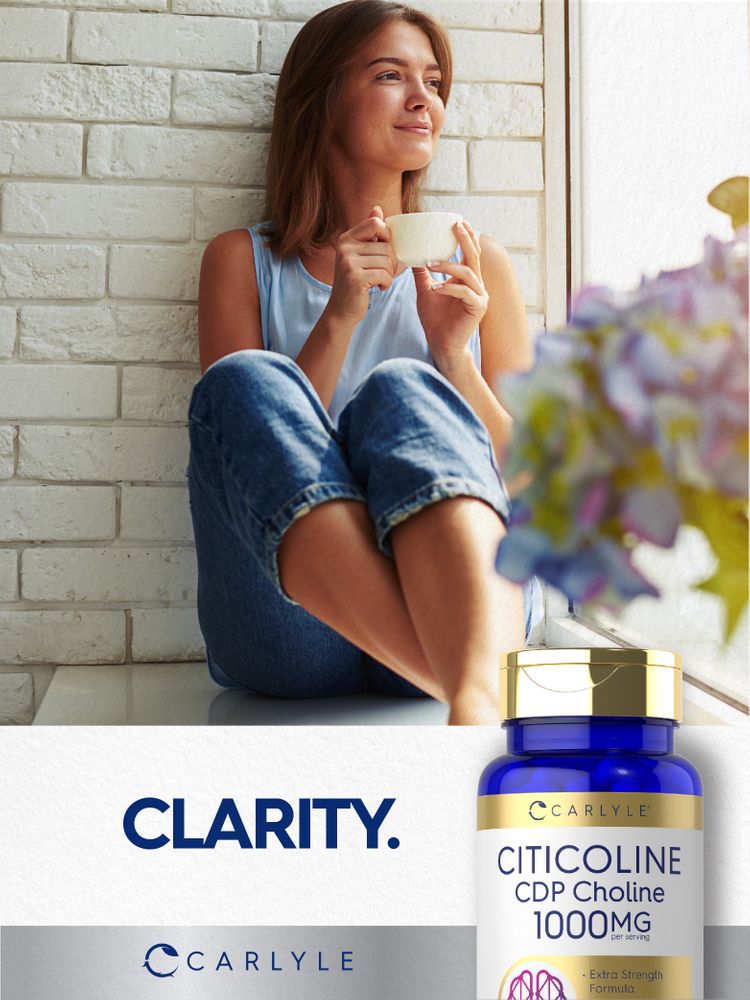 A young woman sits by a window holding a cup, gazing outside with a Citicoline bottle nearby.