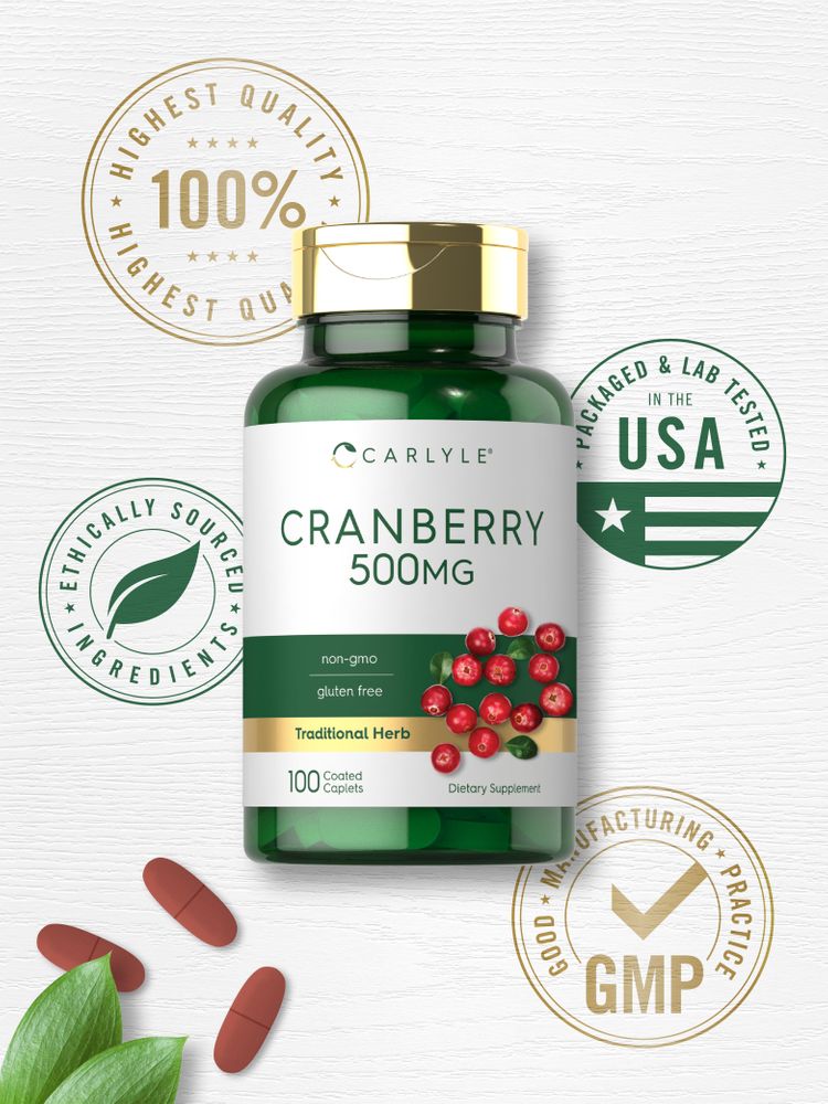 A hand holding Carlyle Cranberry 500mg reddish-brown oval coated caplets on a transparent scale.