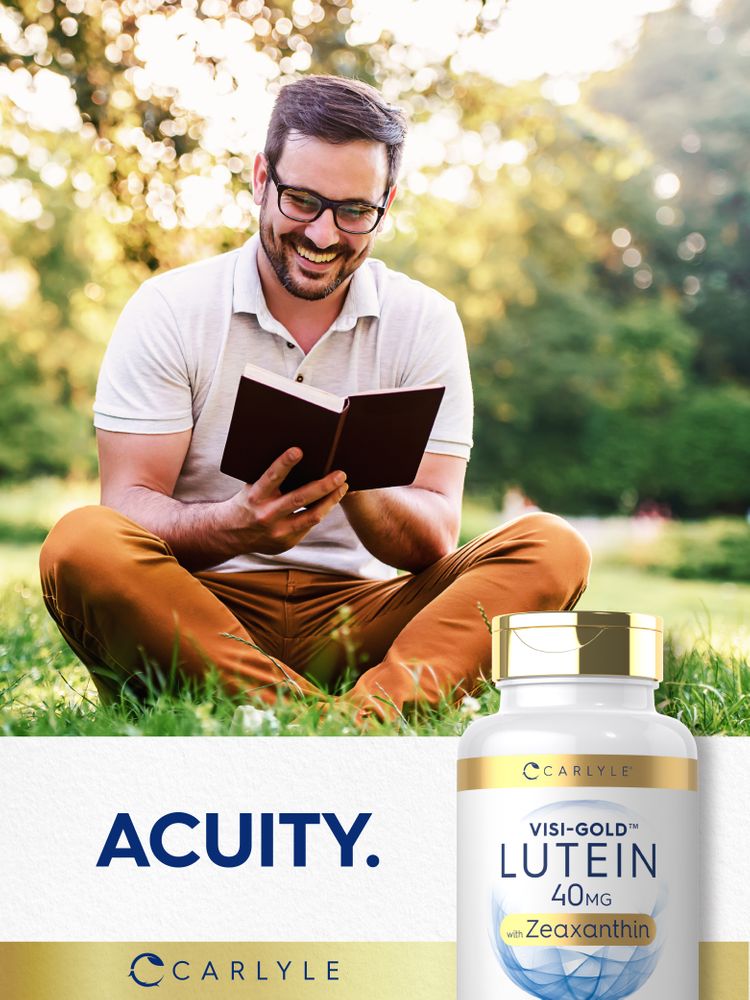 A man in his 30s or 40s sits on grass, smiling and reading a book, next to a Visi-Gold Lutein 40mg bottle.