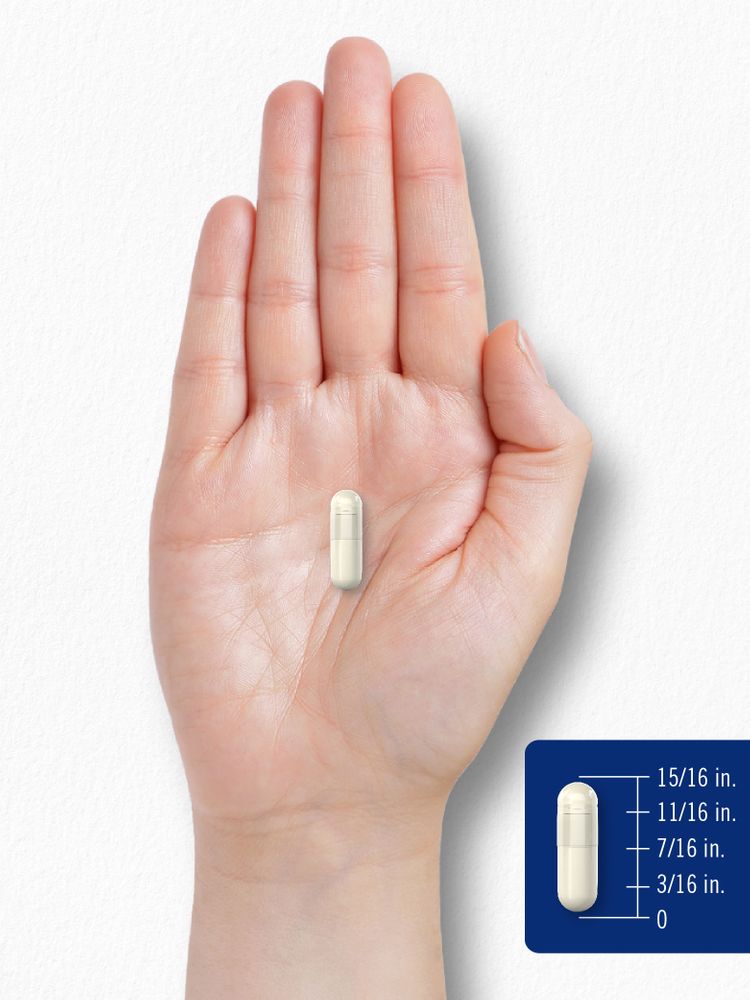 A hand holding a capsule measuring 15/16 inches long.