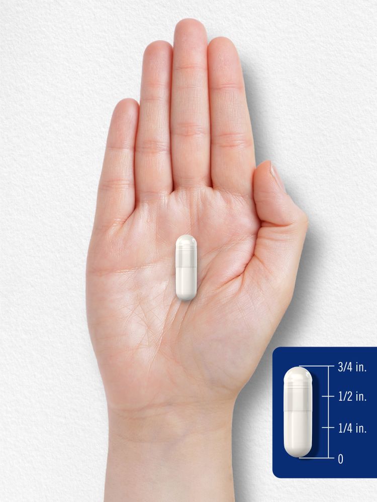 A white capsule, 3/4 inch long, rests on a hand, showing its size and scale.