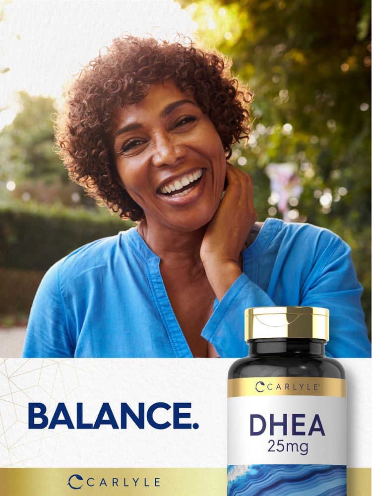 A smiling middle-aged Black woman outdoors holding a Carlyle DHEA bottle.