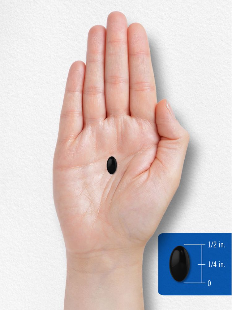 A black softgel measuring half an inch long and a quarter inch wide is shown for scale in a hand.