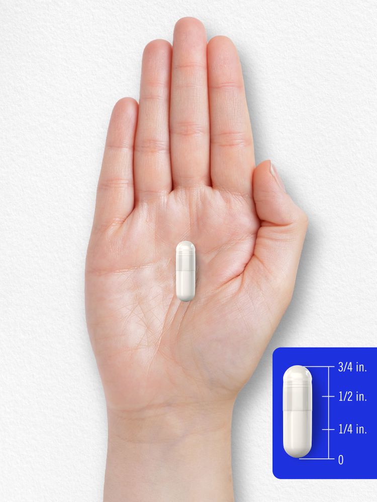 A white capsule in a hand, measuring 3/4 inch long.
