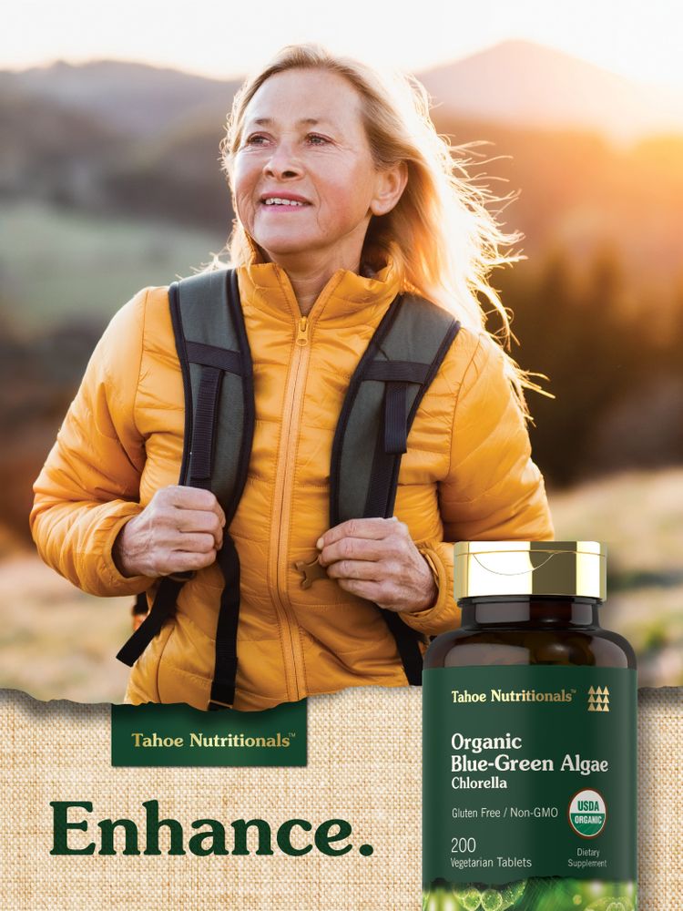 Older woman hiking outdoors holding a bottle of Tahoe Nutritionals Organic Blue-Green Algae Chlorella.