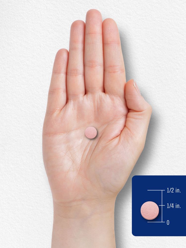A pink round tablet measuring one-fourth inch in diameter is placed on a hand scale.
