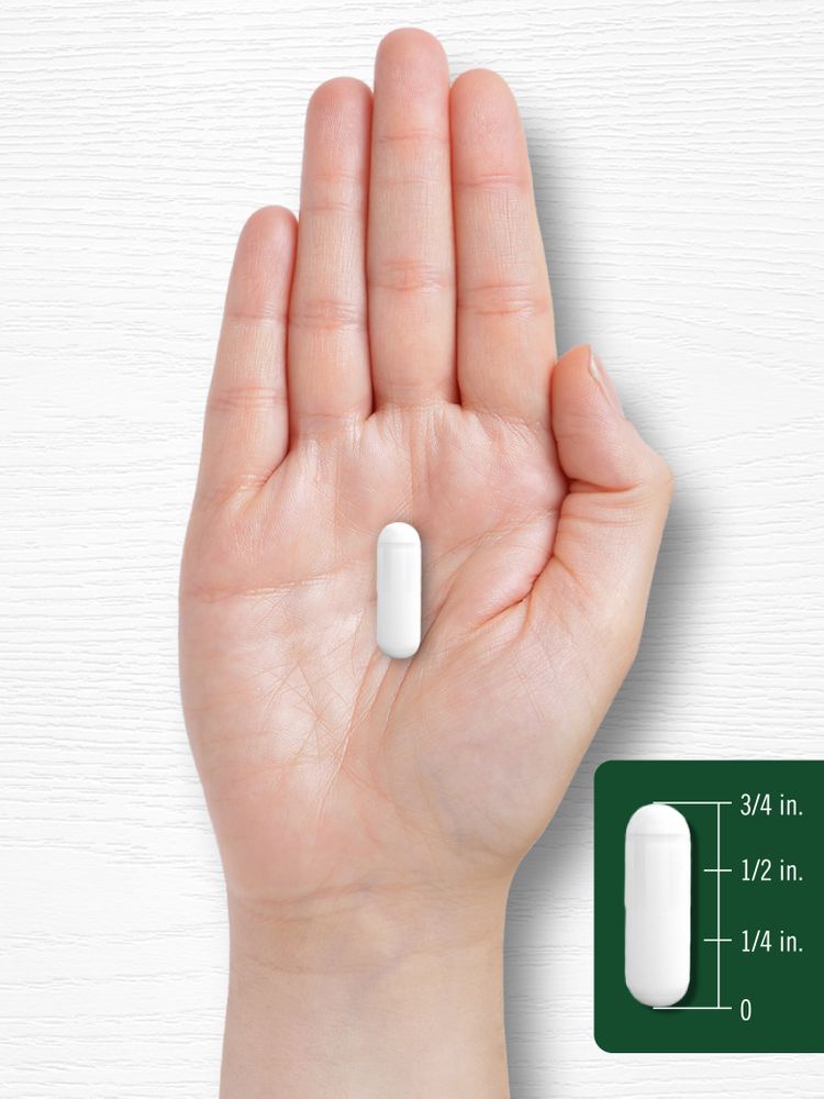 A white capsule, measuring 3/4 inch long, is displayed on a hand for scale against a bulk background.