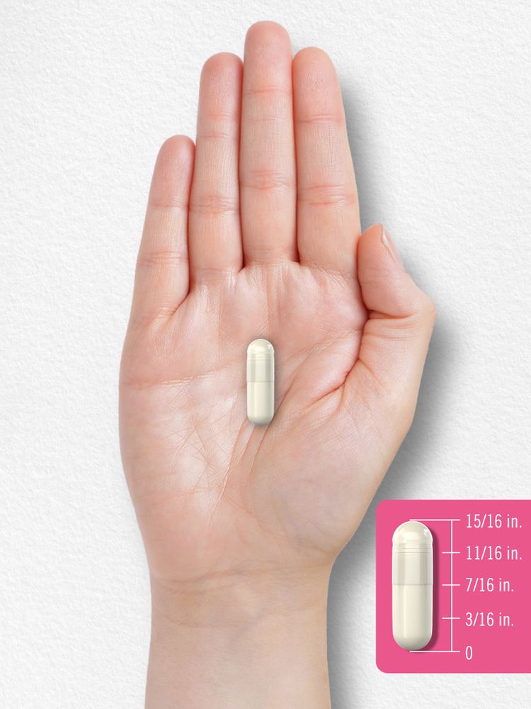 A hand holds a capsule measuring 15/16 inches.