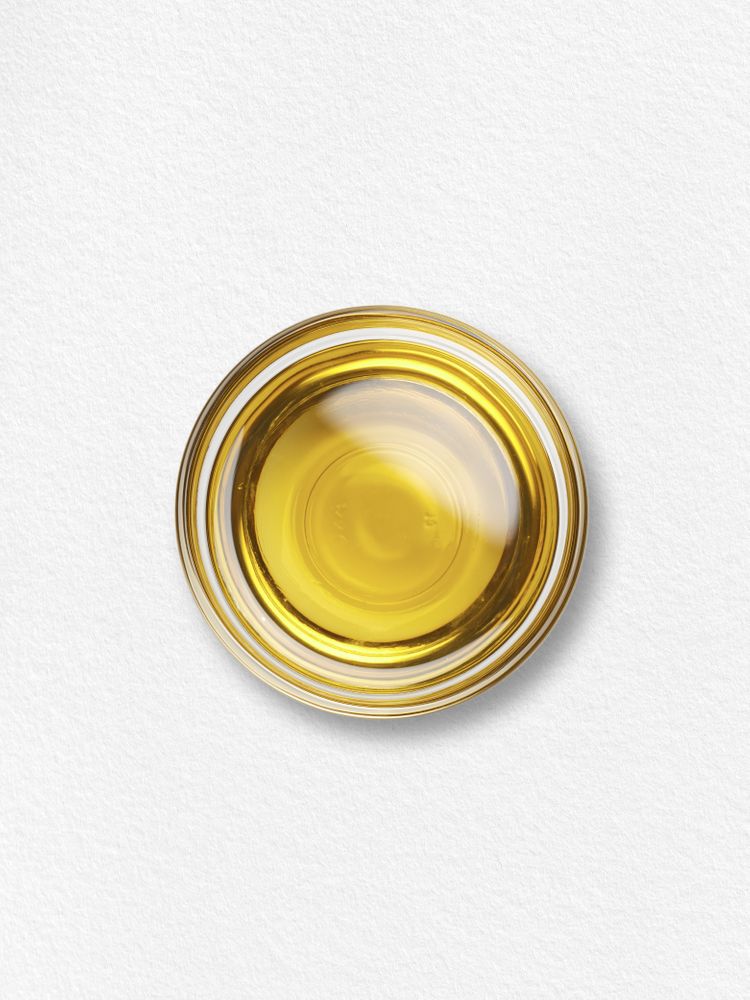 A clear glass bowl of golden yellow Carlyle Vegan Omega 3 6 9 liquid on a white textured background.