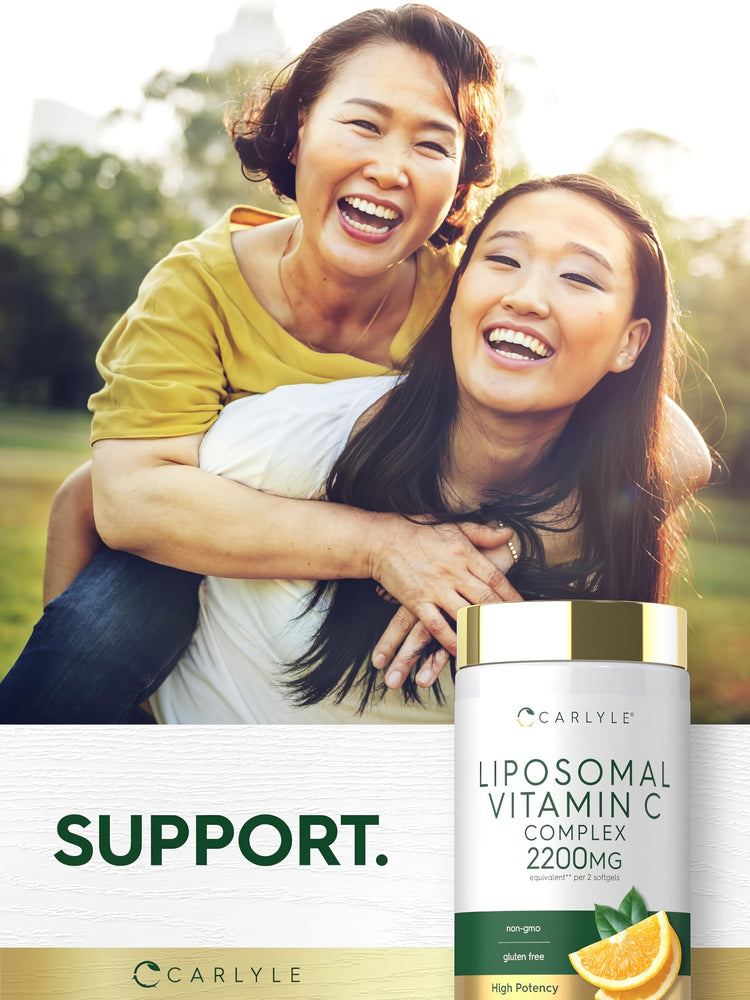 Two women outdoors laughing and embracing with a Carlyle Liposomal Vitamin C bottle visible in the foreground.