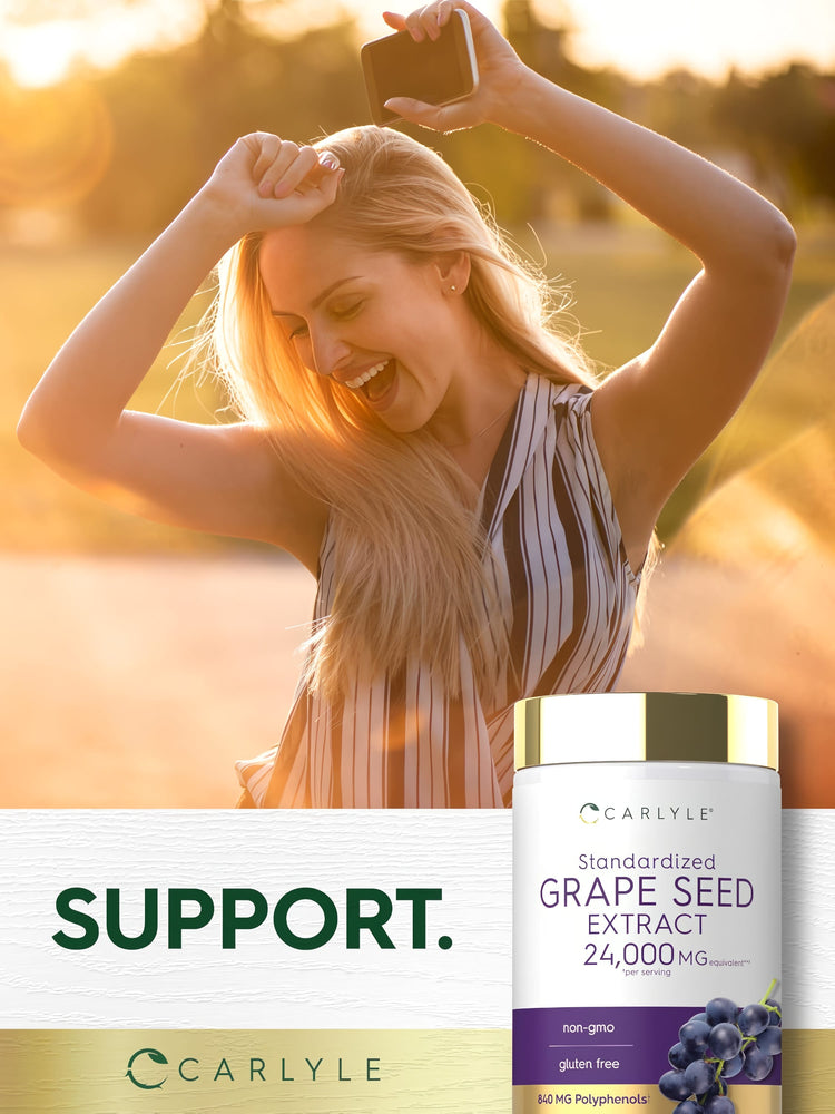 A young woman smiles and dances outdoors in sunlight, holding a Carlyle Grapeseed Extract bottle.