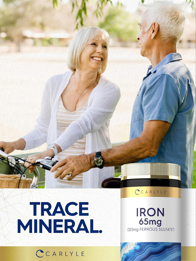 Elderly woman and man smiling in a park with a bicycle, next to a bottle of Carlyle Iron 65mg.
