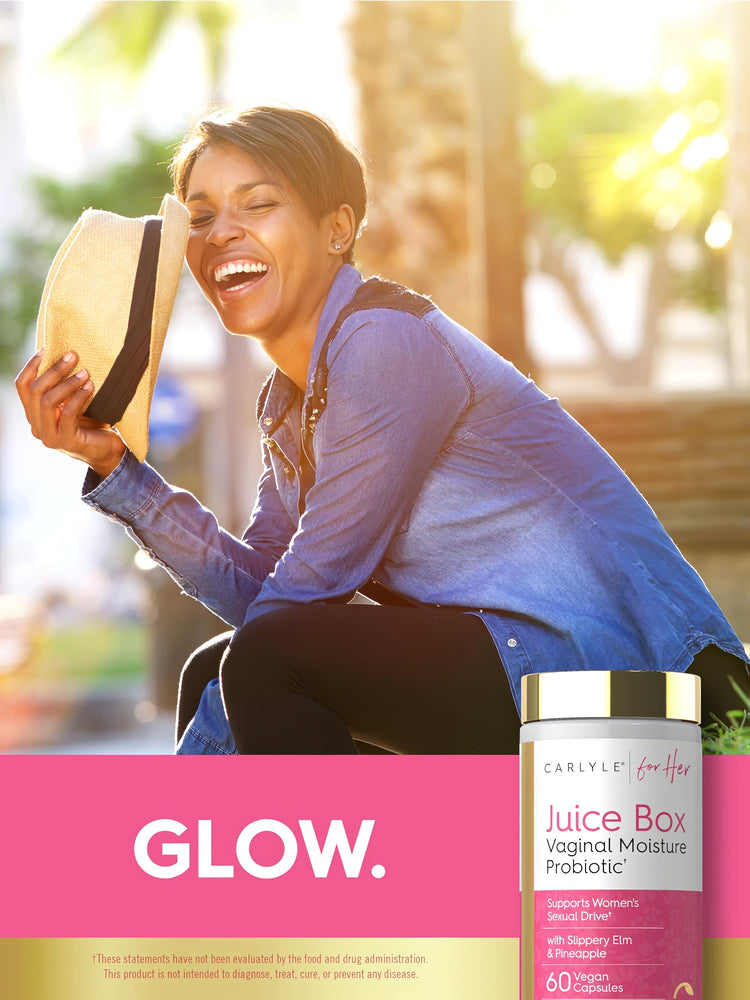 A laughing African American woman holds a hat in sunlight beside a Carlyle Juice Box Vaginal Moisture Probiotic bottle.