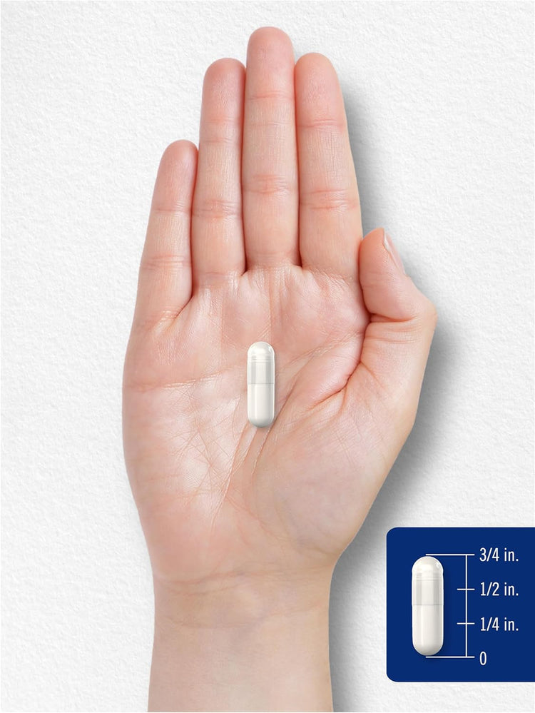 A white capsule measuring 3/4 inch long rests on a hand with a superimposed scale.