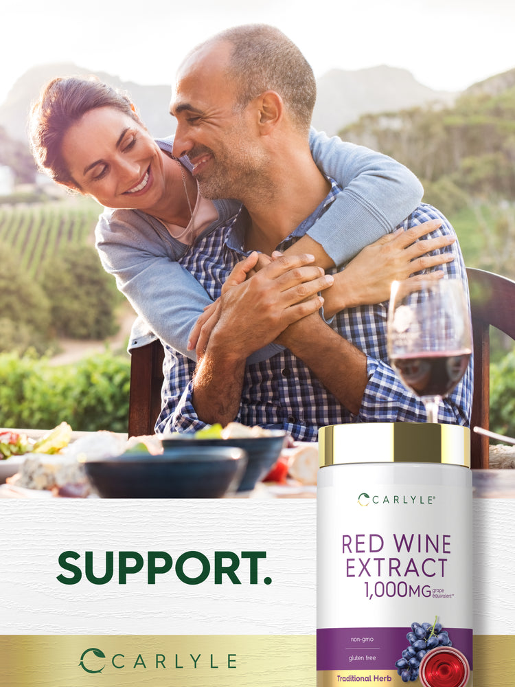 Middle-aged couple smiling and hugging outdoors at a table with food and a Carlyle Red Wine Extract bottle.