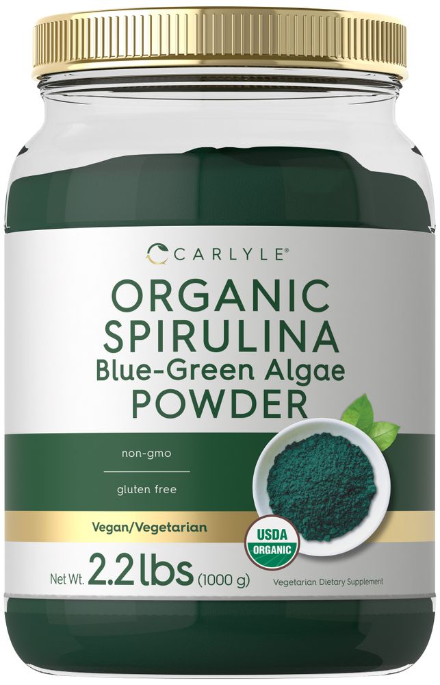 Carlyle Organic Spirulina Blue-Green Algae Powder in a 2.2 lbs (1000 g) jar, shown on a hand scale.