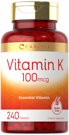 Hand holding Carlyle Vitamin K 100 mcg in a bottle containing 240 tablets, showcasing product packaging and quantity.