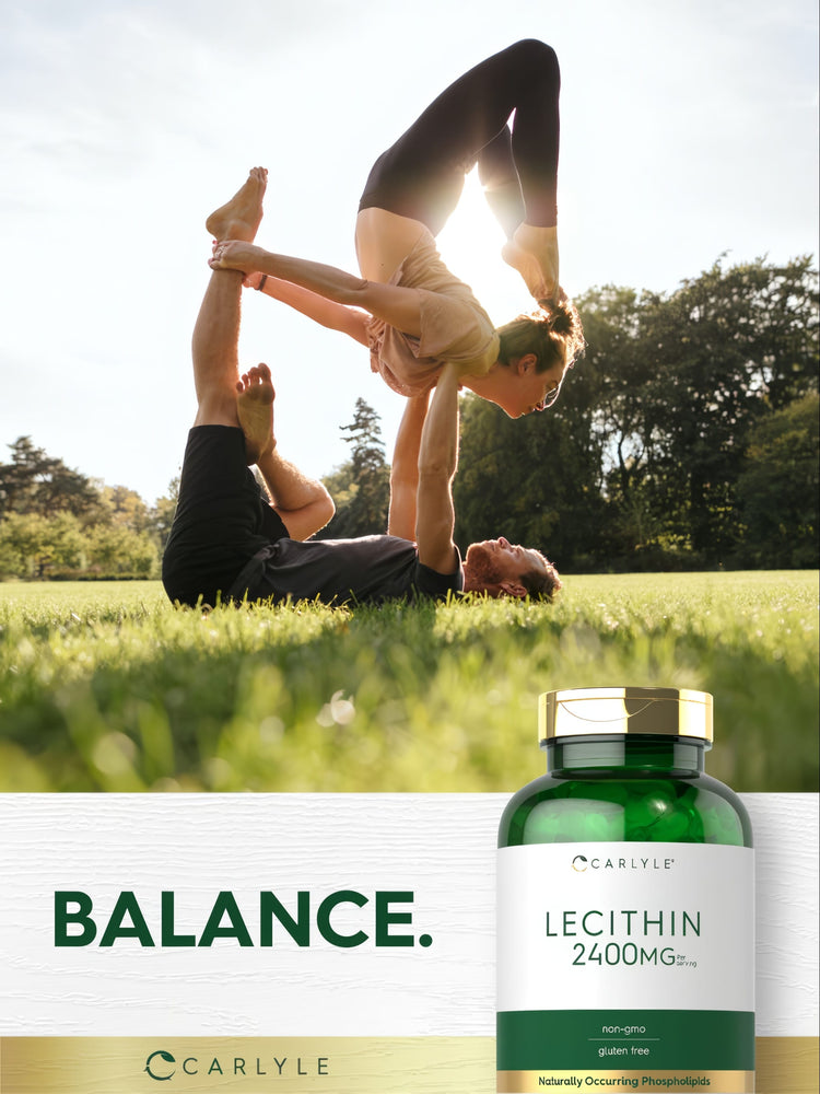 Young adult male and female performing acro yoga in a park, with a bottle of Carlyle Lecithin nearby.