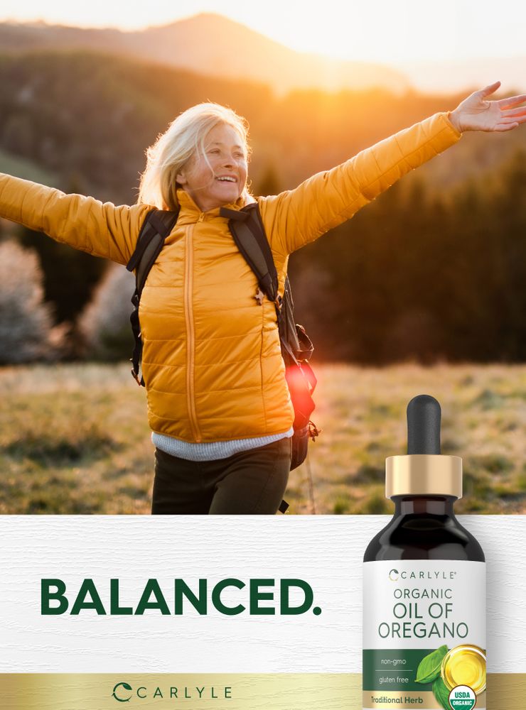 Older woman with arms outstretched hiking at sunset, beside a Carlyle Organic Oil of Oregano bottle. Text 'BALANCED.' also visible.