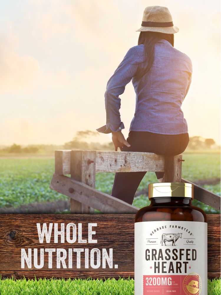 Adult woman on a wooden fence at sunset with a bottle of Grass Fed Heart supplement in the foreground.