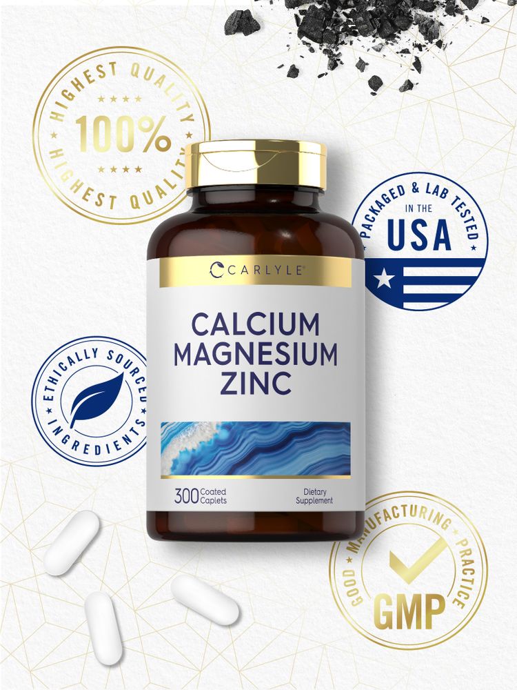 A hand holds three white coated Carlyle Calcium Magnesium Zinc caplets on a scale.