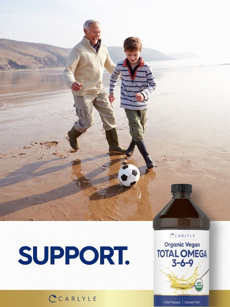Elderly man and young boy playing soccer on a beach with a bottle of Carlyle Vegan Total Omega 3-6-9 liquid.