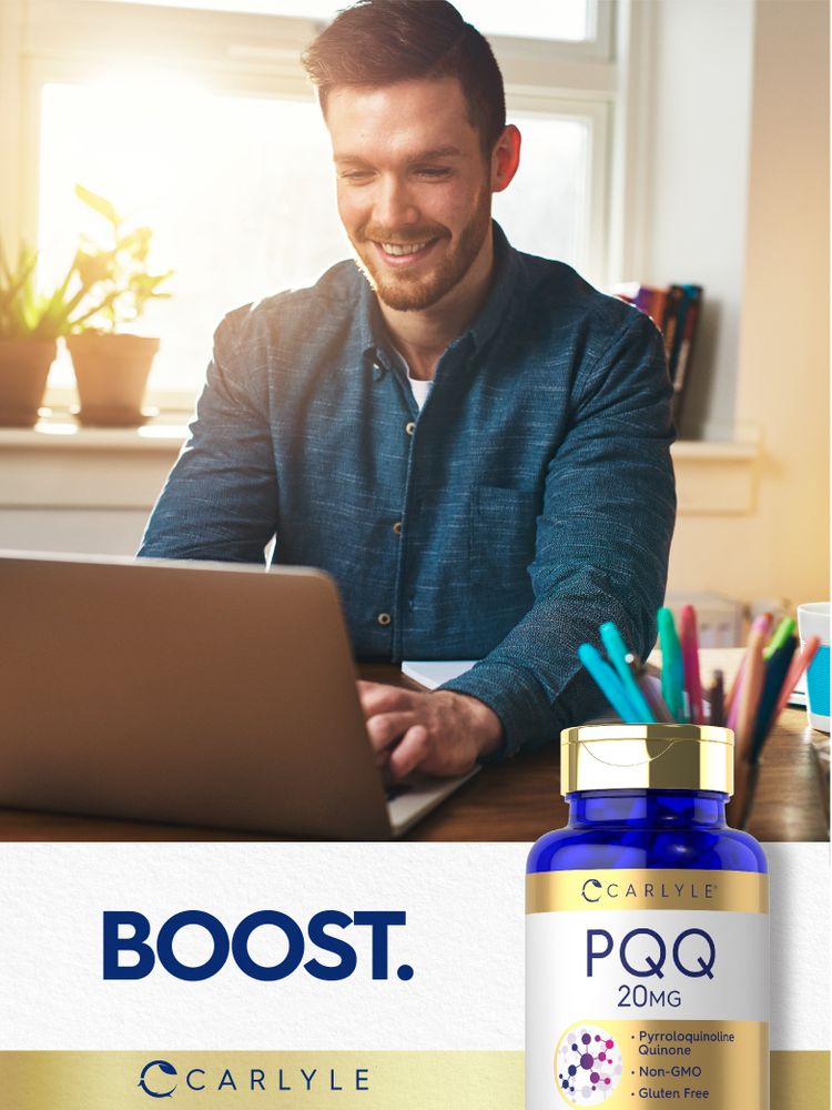 A young man smiles and types on a laptop with a Carlyle PQQ 20MG bottle next to him.
