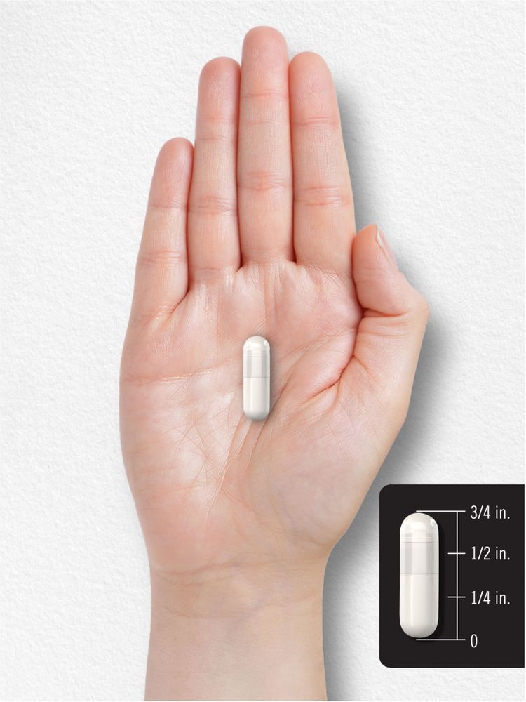 A white capsule measuring 5/8 inch in length is displayed on a scale in a close-up view.