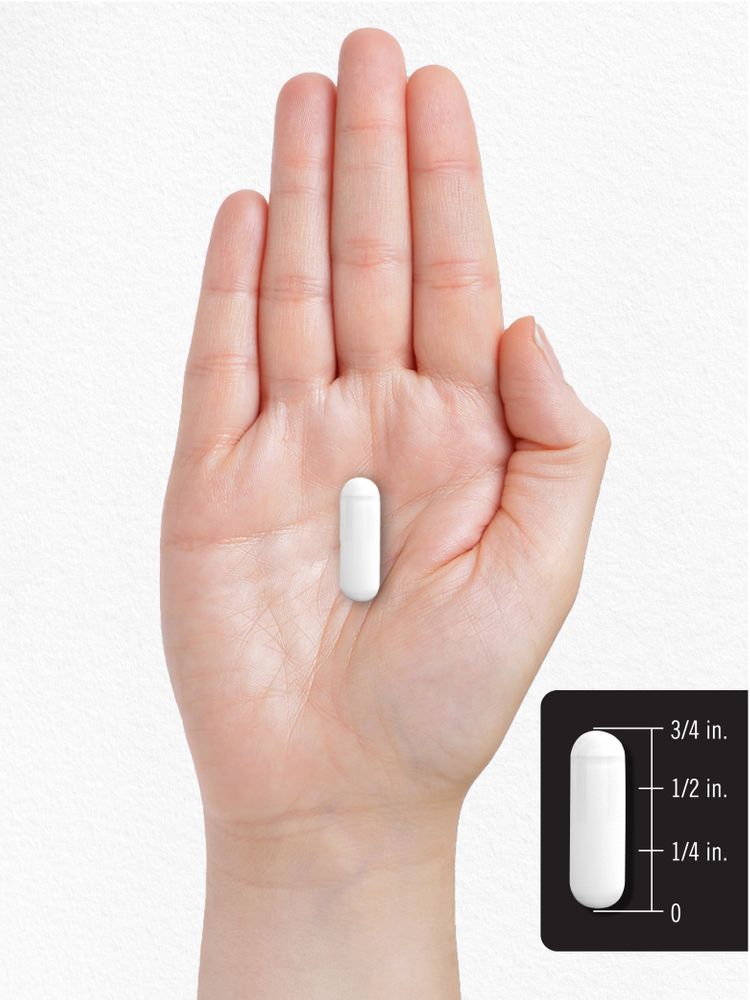 A white capsule, 3/4 inch long, rests on an open palm next to a 3/4 inch measurement scale.