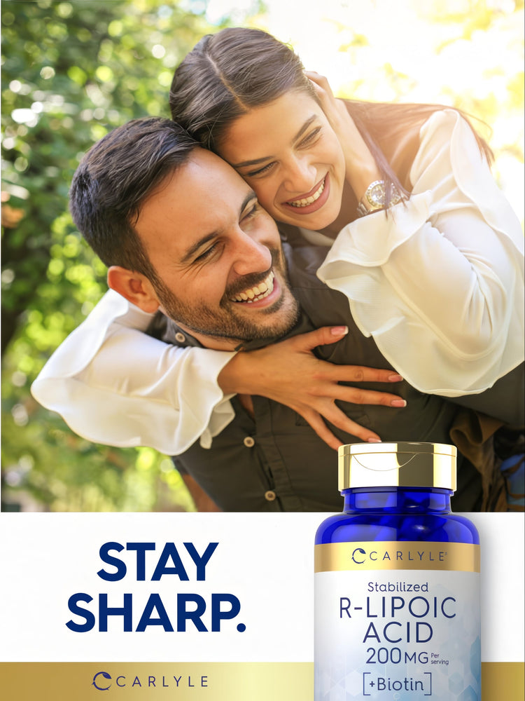 A young adult man and woman are embracing and laughing outdoors, holding a Carlyle R-Lipoic Acid bottle.