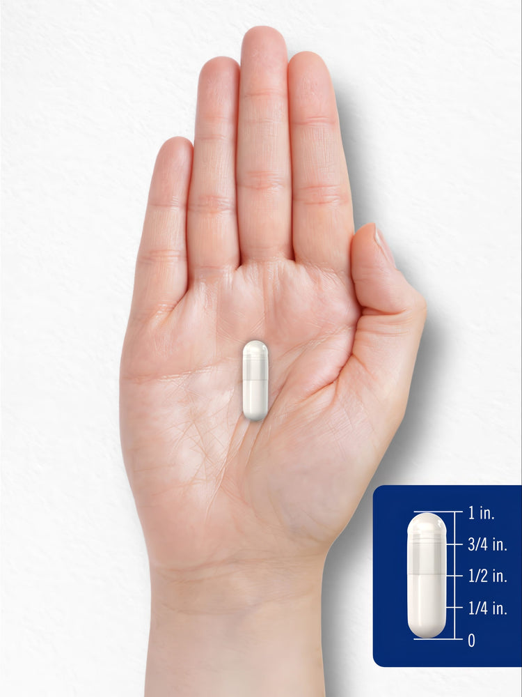 A 3/4 inch white capsule rests on an open hand, indicating scale.