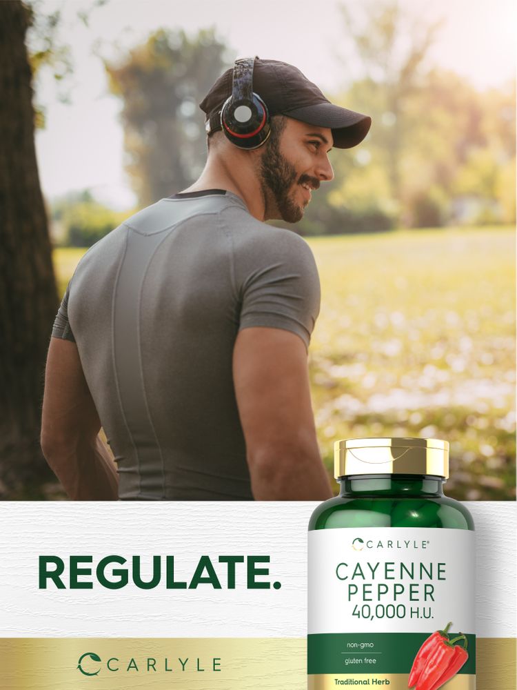 A young man smiles outdoors holding a Cayenne Pepper bottle.