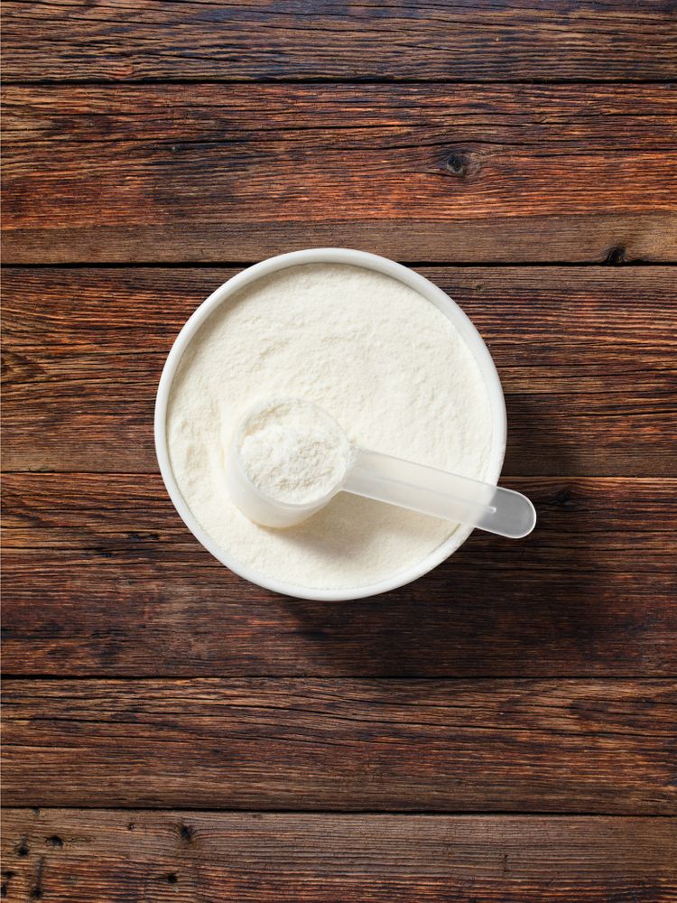 A white bowl filled with Multi Collagen Protein powder and a white scoop on top.