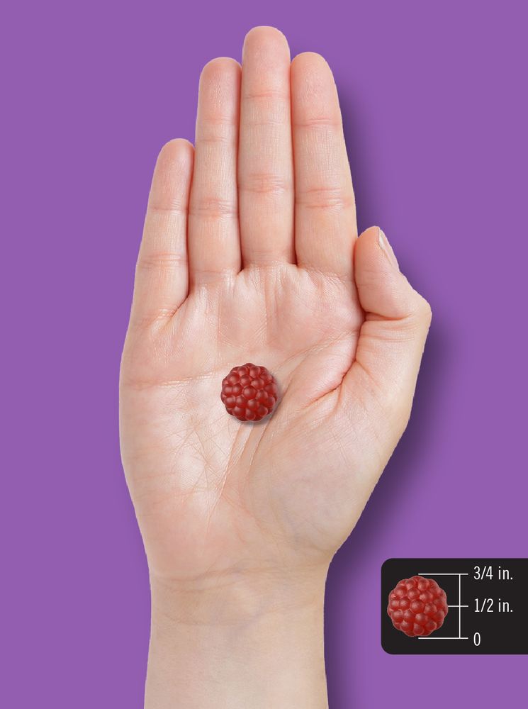 A single red gummy sits in a hand, measuring 1/2 inch tall.