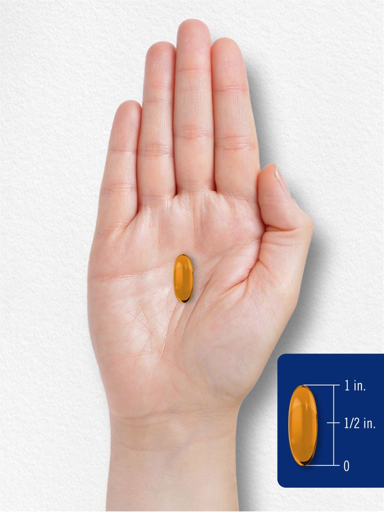 An orange softgel rests on a hand, measuring between half an inch and one inch.