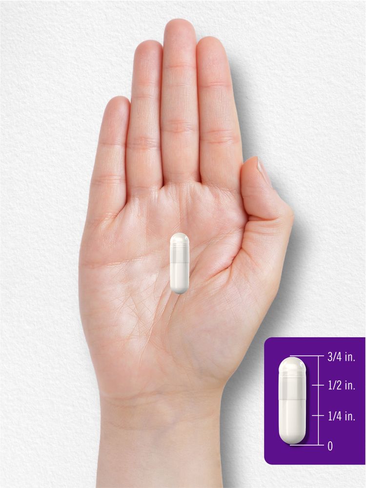 A hand holding a capsule that measures three-quarters of an inch in length.