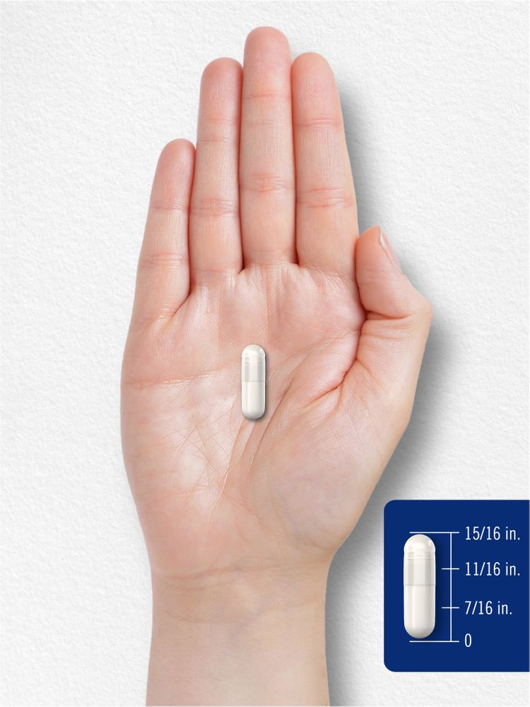 A 15/16 inch long white capsule displayed on a hand-held scale.