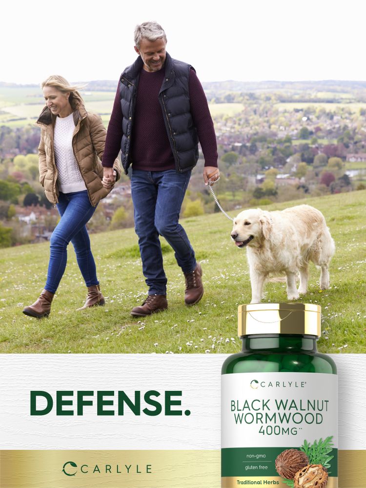Middle-aged couple on a grassy hill walking their golden retriever with a bottle of Black Walnut Wormwood.