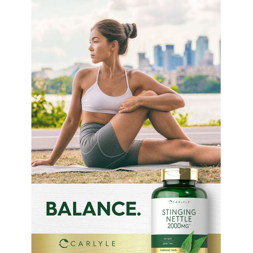 View 6 Young woman doing a seated yoga twist outdoors on a mat near a bottle of Carlyle Stinging Nettle.
