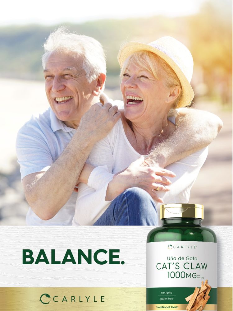 Elderly couple laughing and hugging on a beach, holding a Carlyle Cat's Claw 1000mg supplement bottle.