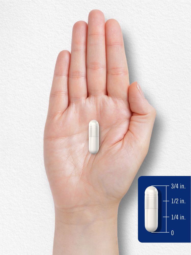 A white capsule, approximately 3/4 inch long, is placed on a hand, highlighting its size.