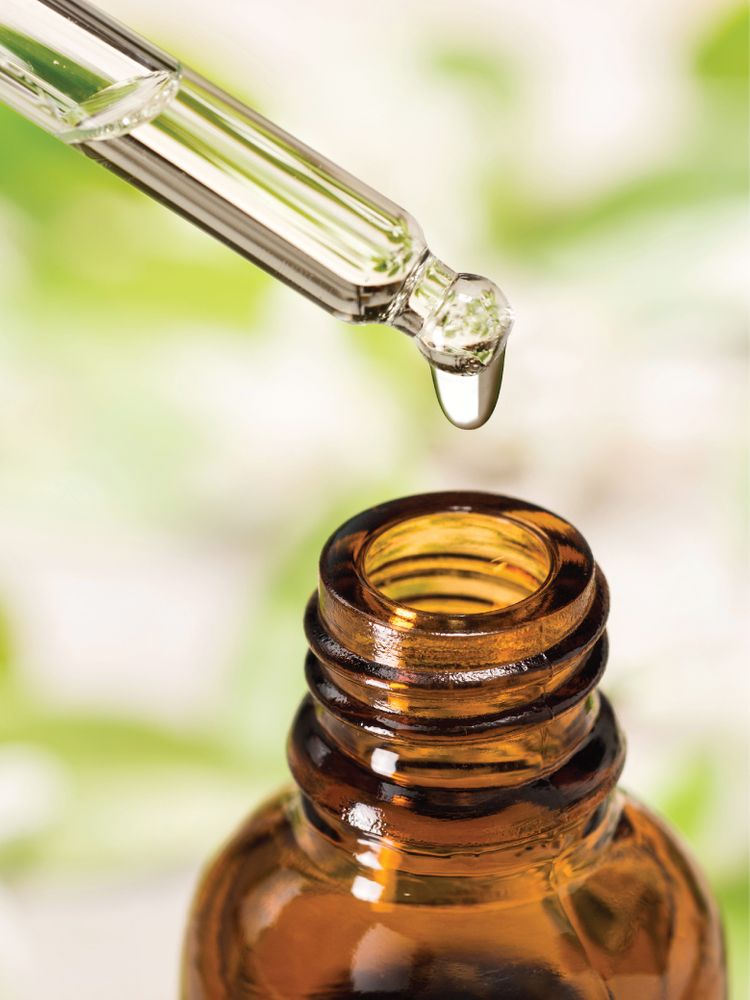 A glass dropper releases a drop of liquid organic nascent iodine into a brown glass bottle.