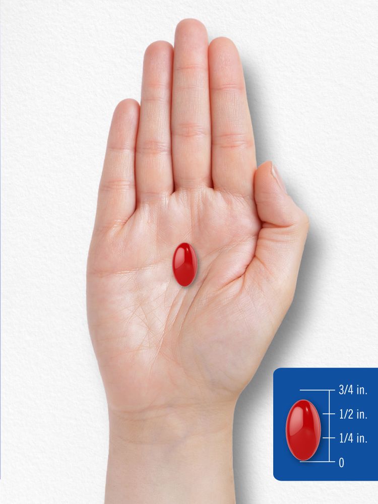A red oval softgel, approximately three-quarters of an inch long, on a bulk scale with a hand for size reference.