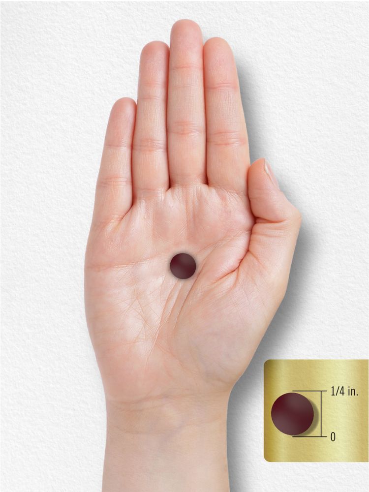 A small, dark red tablet, 1/4 inch in diameter, rests on a person's palm, conveying its size.