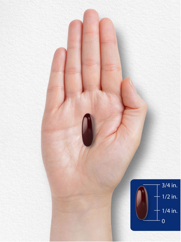 A dark red softgel capsule approximately three-quarters of an inch long is displayed on a hand for scale.